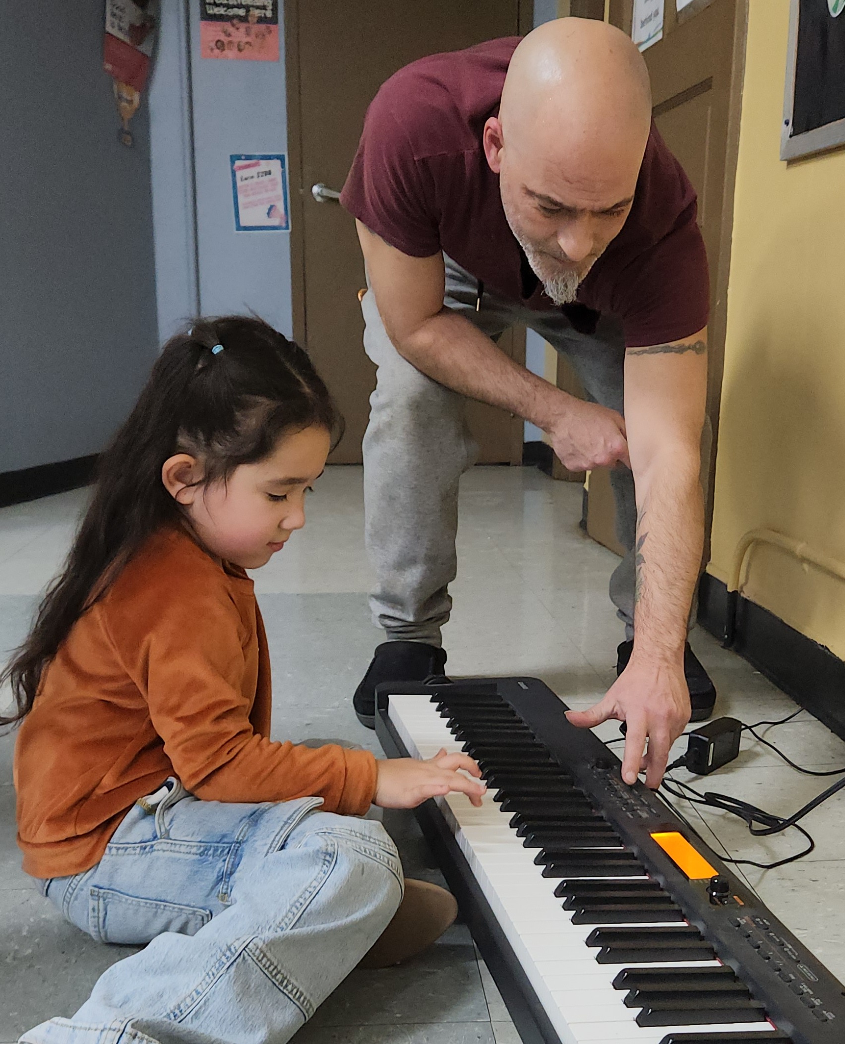 Little girl learning to play the keyboard with her music teacher