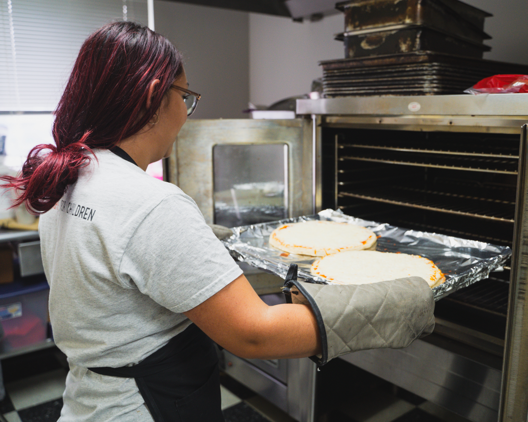Our on-site chef placing homemade pizzas into the oven