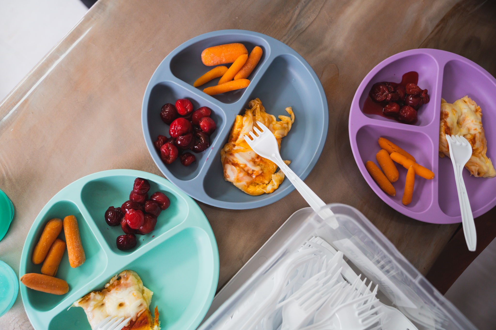 Colorful divided plates of fruit, carrots and a hot homemade lunch
