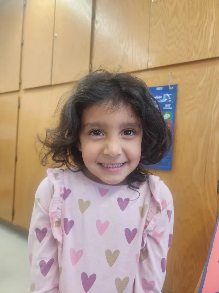 A young girl smiling brightly in the classroom
